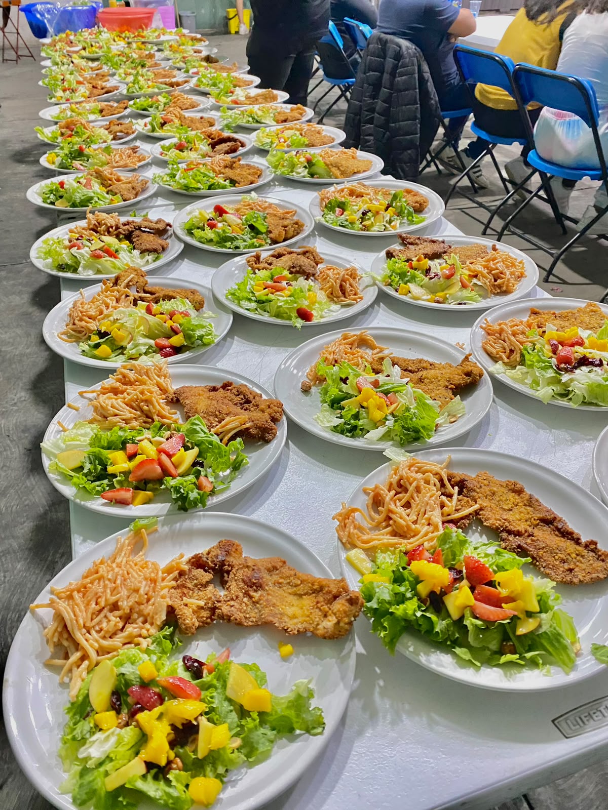 Charolas servidas con milanesa empanizada, ensalada y pasta para un banquete grande
