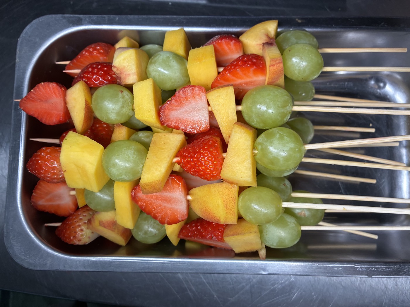 Brochetas de fresa, uva verde y durazno listas para servir