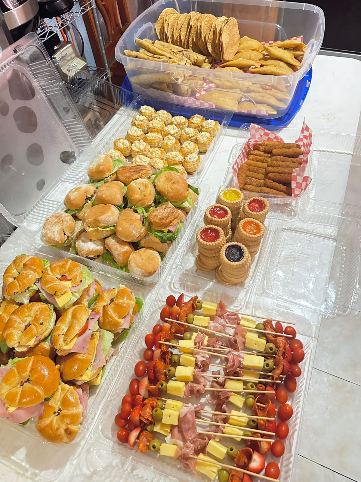 Mesa de bocadillos con canapés, mini tortas, taquitos dorados y brochetas de queso y jamón serrano