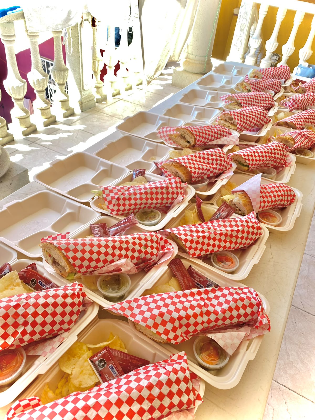 Tortas para llevar empacadas individualmente con papas y salsa, listas para repartir en un evento